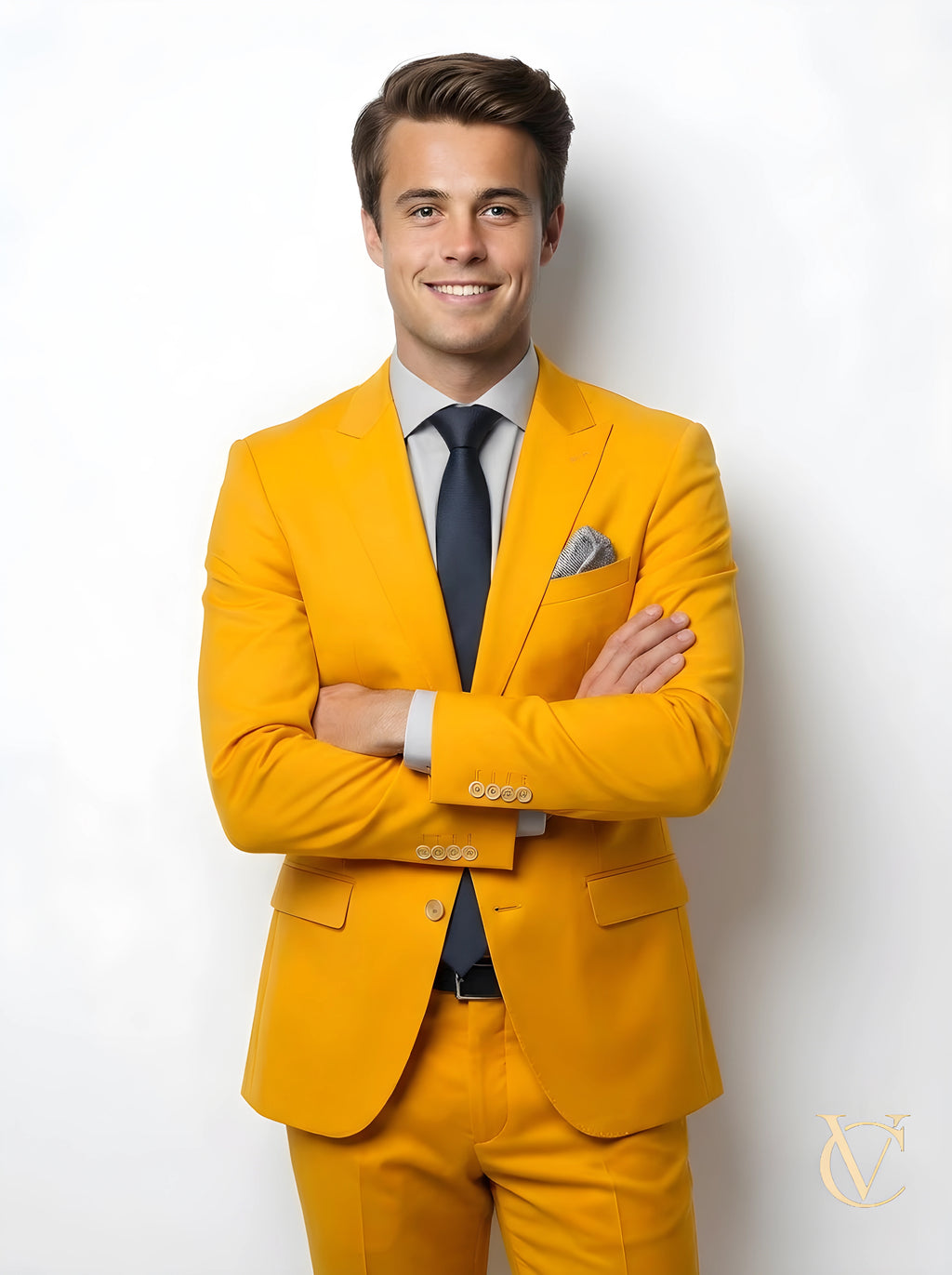 A young man wearing a modern 2-Piece Suit - Yellow | Vellure Couture with a navy tie and light blue shirt, smiling confidently against a white background, showcasing a tailored fit.