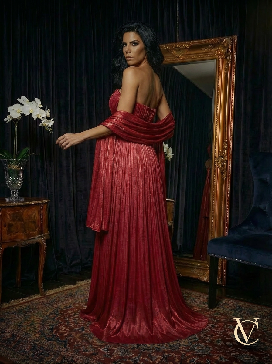 Woman wearing elegant Pleated Gown - Burgundy | Vellure Couture with a matching shawl, standing in a luxurious room with vintage furniture and a large ornate mirror.